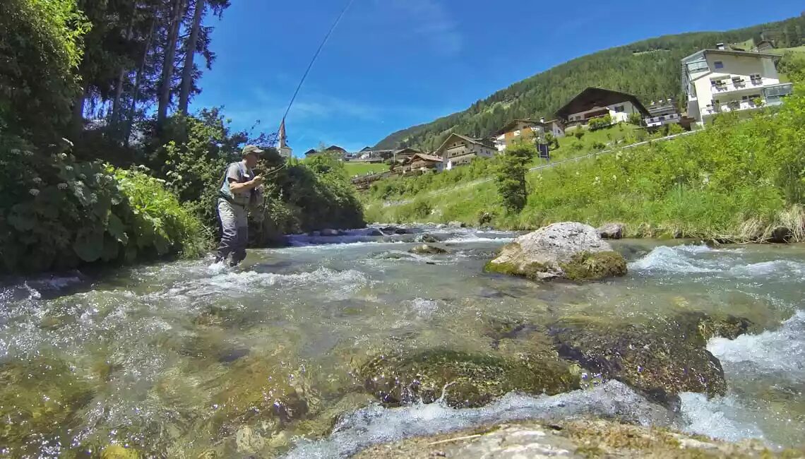 Pescatore a mosca nelle acque limpide del torrente Cordevole