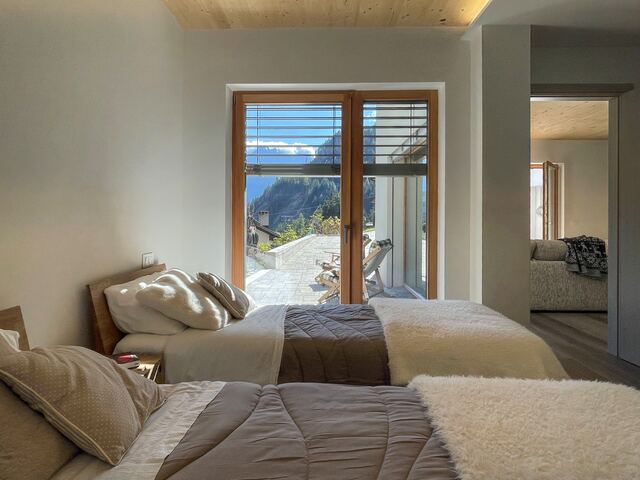 Camera da letto con plaid in lana e finestra sul bosco