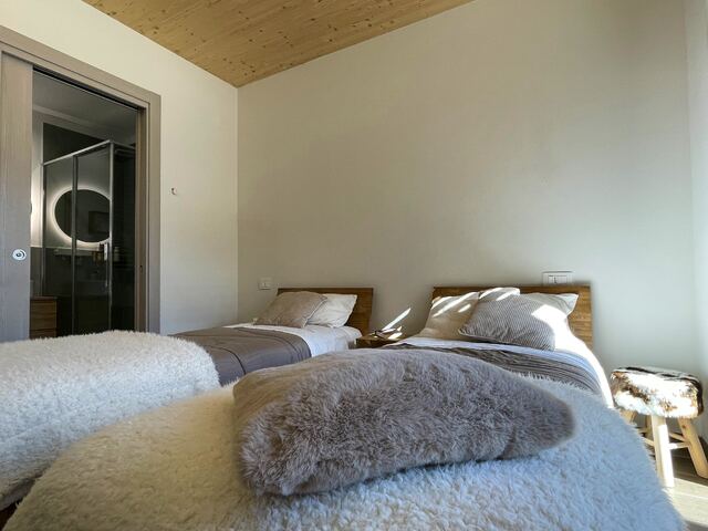 Letto con plaid in lana e bagno en-suite sullo sfondo