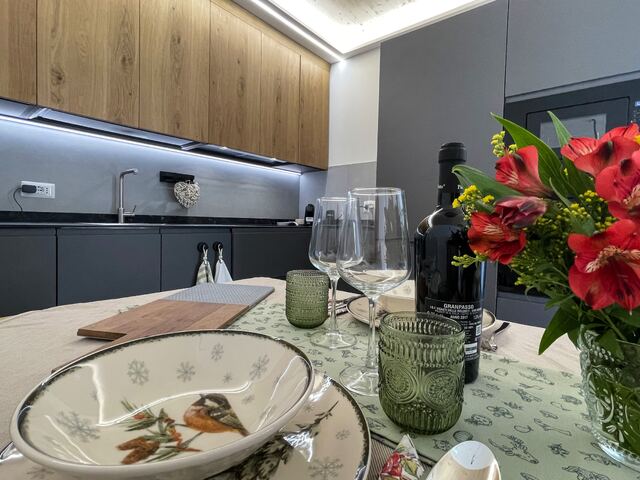 Dettaglio della cucina con fiori rossi e calice di vino