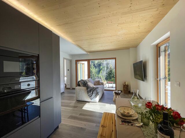 Soggiorno e cucina open space con soffitto in legno e vista sulle montagne